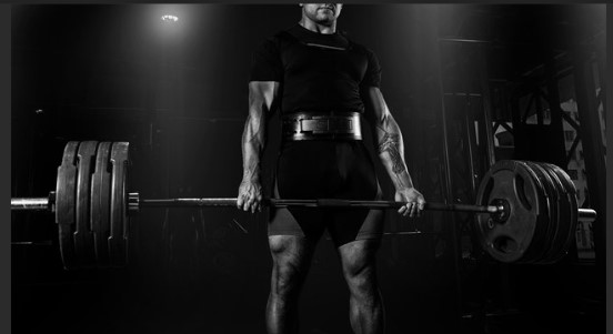Security candidate performing a heavy barbell deadlift in a gym.